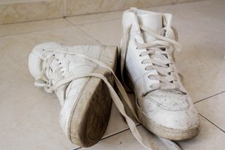 A pair of white shoes with mud on them