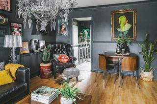 dark living room with a mid century dining set, black walls and quirky art prints