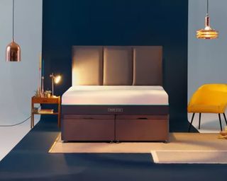 A mattress laying on a bed with a navy blue headboard in a contemporary bedroom