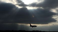 plane flies under dark grey sky