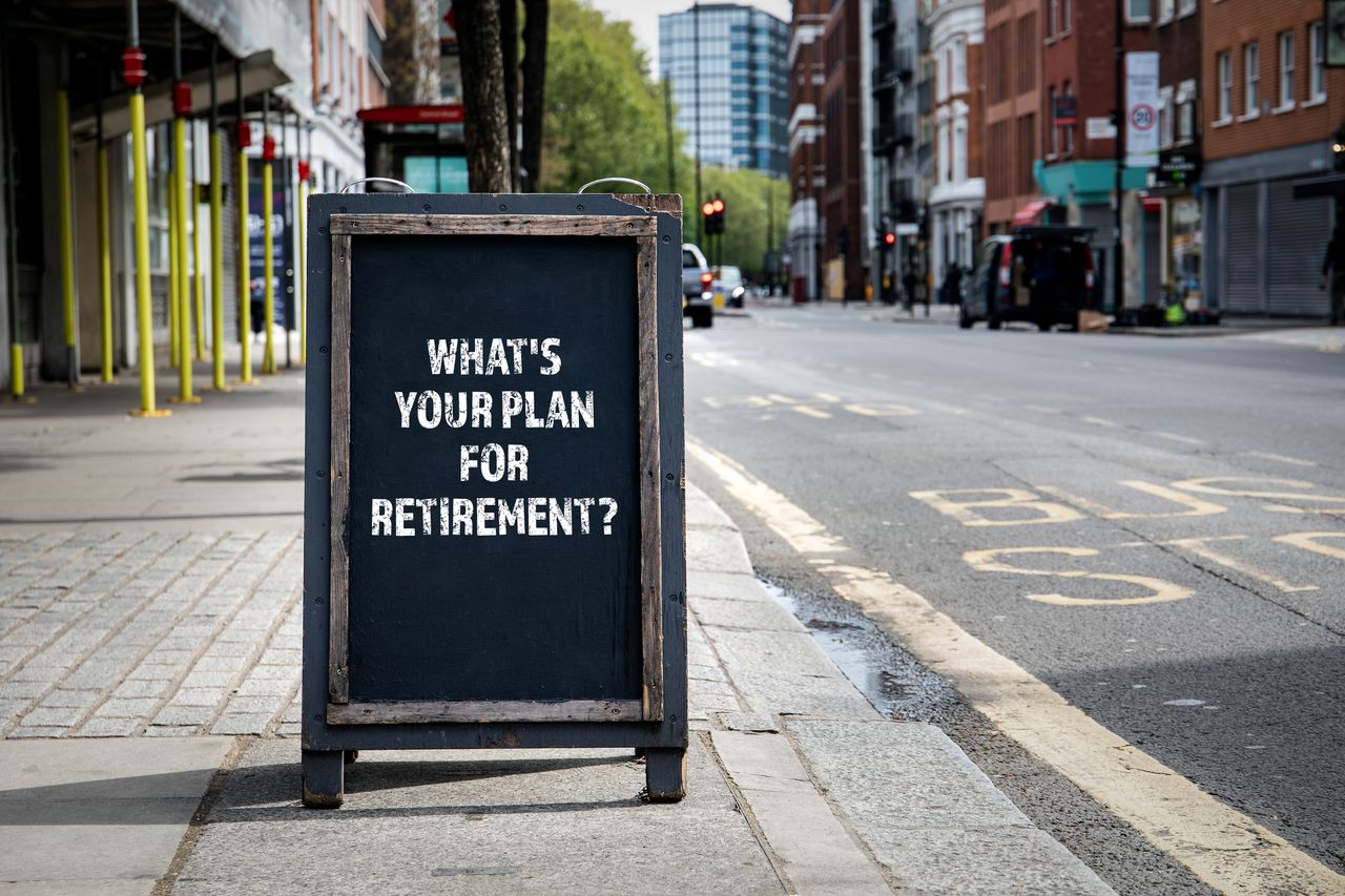 A foldable wooden and slate store sign on the street reads &quot;What is Your Retirement Plan?&quot;