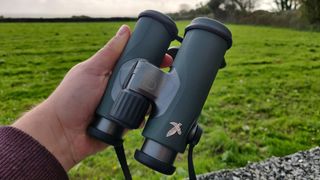 Swarovski CL Companion 10x30 binoculars being held in man's hand outdoors