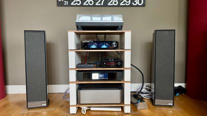 Ruark Audio Talisman-R floorstanding speakers either side of a hi-fi system, all on a wooden floor.