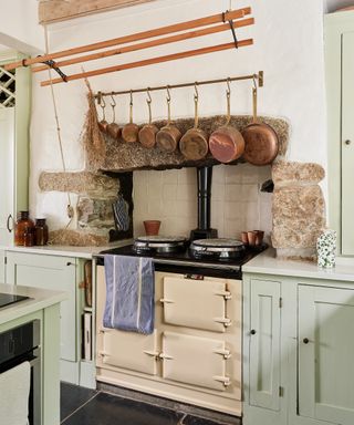 Cream range cooker in the original fireplace of a farmhouse kitchen, with classic wooden clothes airer hung above