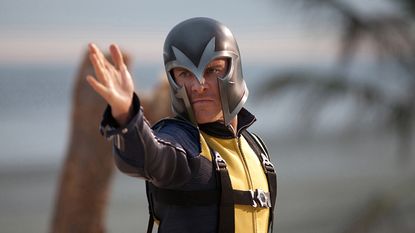 A still from X-Men: First Class of Magneto, played by Michael Fassbender, wearing a helmet and holding his arm out.