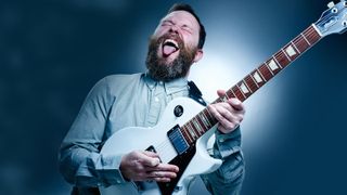 Man playing the Epiphone Les Paul Studio with blue background