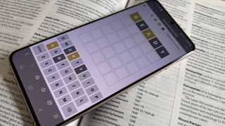 A phone displaying a game of Wordle, on top of a dictionary