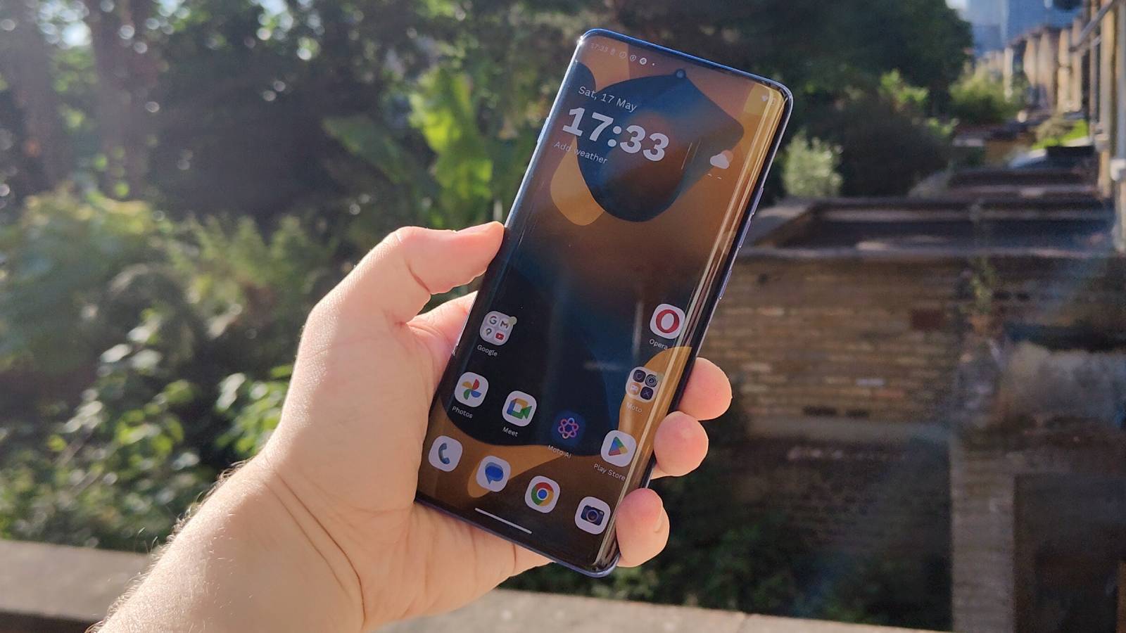 The Motorola Edge 60 Pro above a leafy garden