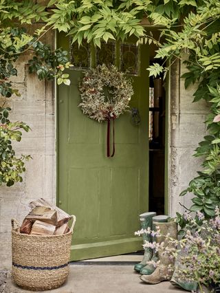 green painted door with a dried flower wreath