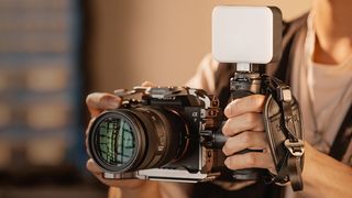 Someone holding a Sony camera with SmallRig Rotating Side Handle with Trigger Rec and light attached