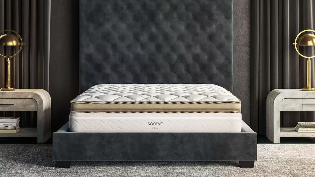 Saatva Solaire Mattress against a gray headboard. 