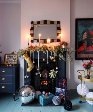 Festive guest bedroom with styled fireplace featuring garden foliage, baubles hung on ribbons and disco balls and drinks trolley