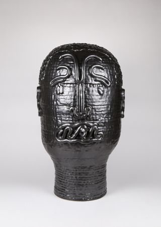 Black ceramic sculpture depicting a human face in stylized form