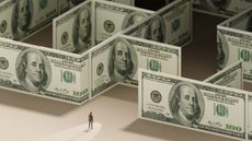 A businessman stands at the start of a maze made out of hundred-dollar bills.