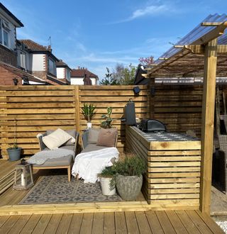 Outdoor kitchen with wood panelling, tiled worksurface and grey seating