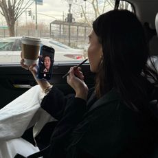 A woman applying lip liner in the car.