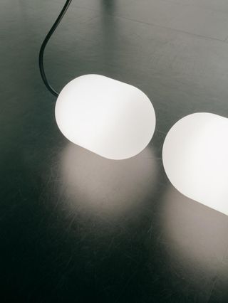 Two large light globes facing each other above a shiny floor.