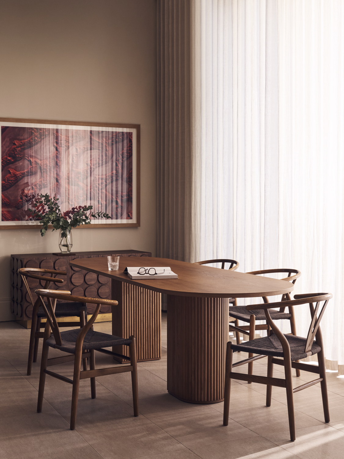 Sleek dining room with oval wood table, wishbone chairs, red abstract artwork and floor-to-ceiling sheer curtains