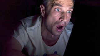 Shocked man sitting in front of laptop screen