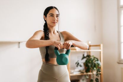 Woman working out with a kettlebell in her living room