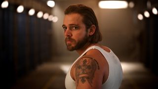 Max Thieriot, wearing a white vest, as Bode Donovan back in jail in Fire Country season 2