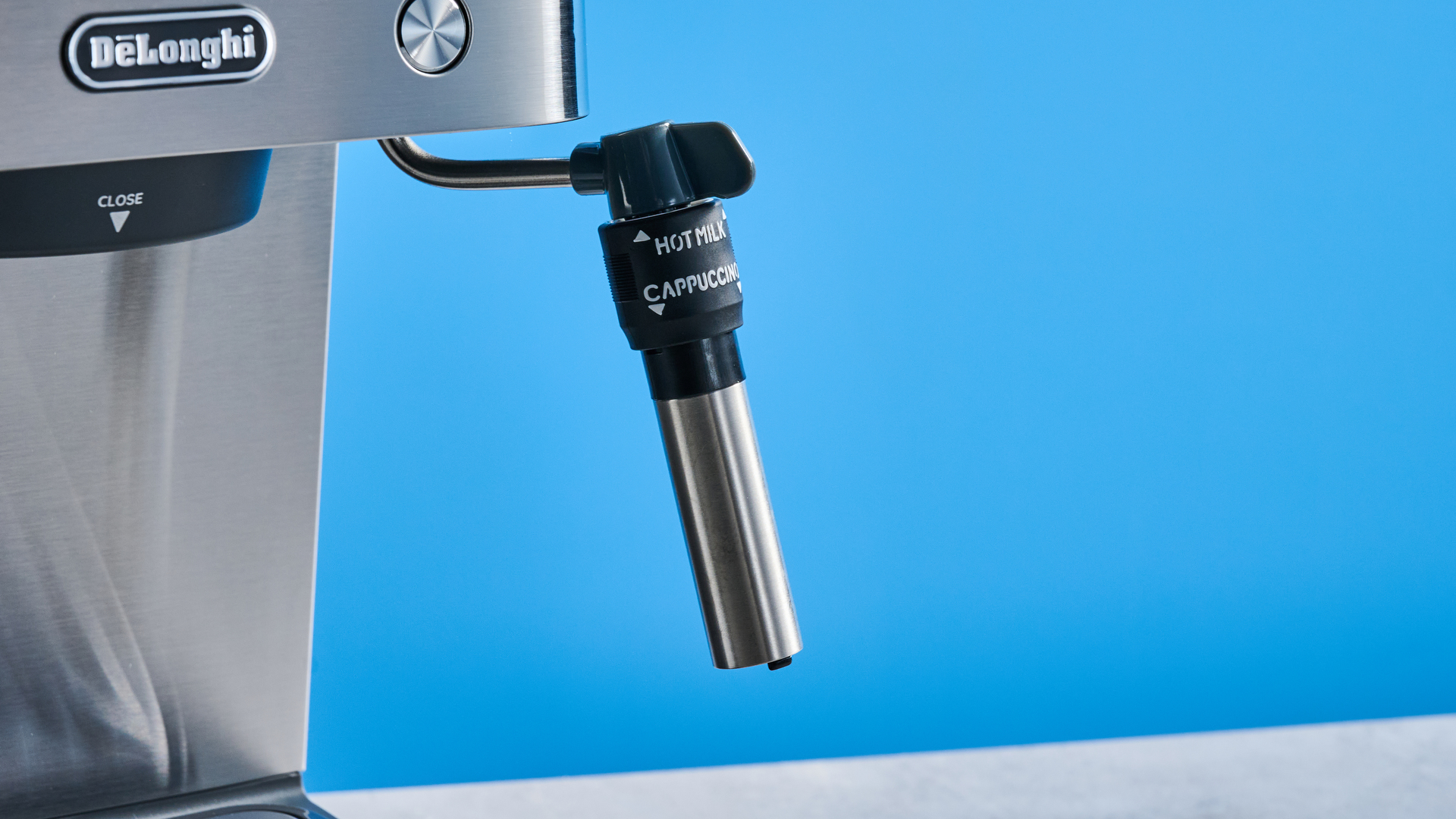 the De'Longhi Linea Classic espresso machine photographed against a blue tom's guide background, showing its silver finish, steam dial, steam wand, portafilter, and accessories