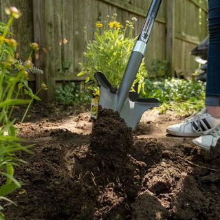 a woman using the root slayer to dig up soil