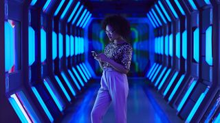 woman using a smartphone in a futuristic corridor
