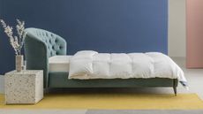 A duvet cover laid on a bed with a teal velvet headboard in a contemporary bedroom