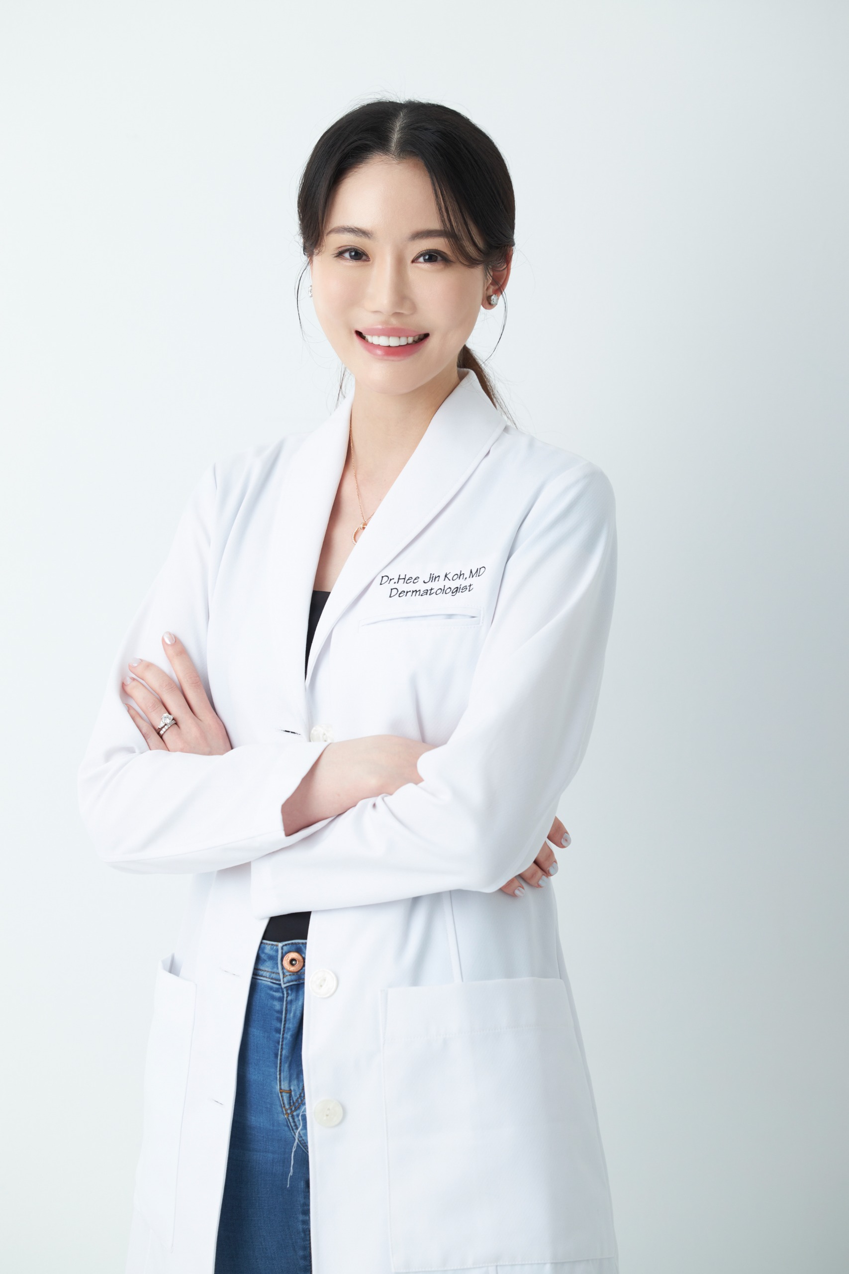 an asian woman wearing a white coat and jeans
