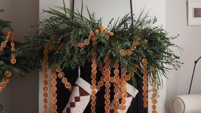 a fireplace decorated with foliage and dried orange garlands