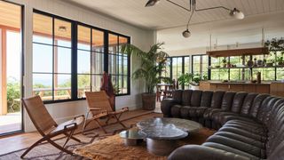 living room with large black leather sofa and earthy color palette