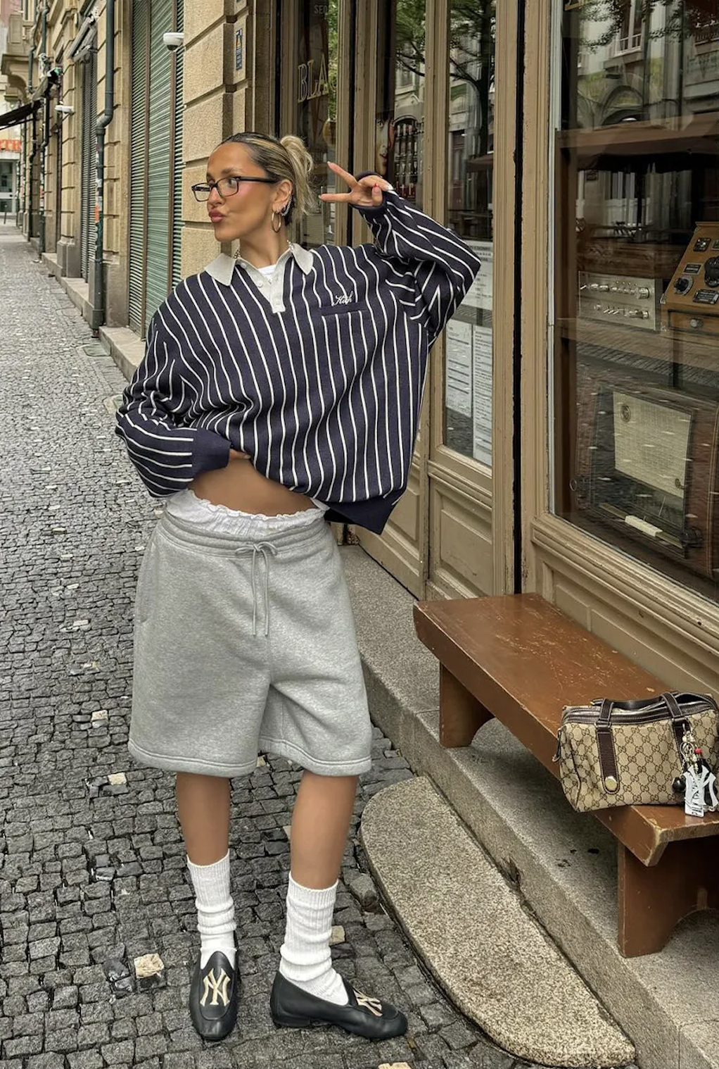 Influencer Sofia Mcoelho in a blue and white striped polo sweater grey shorts and white socks and loafers.