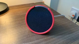 Amazon Echo Pop on a table, with a pink sleeve on
