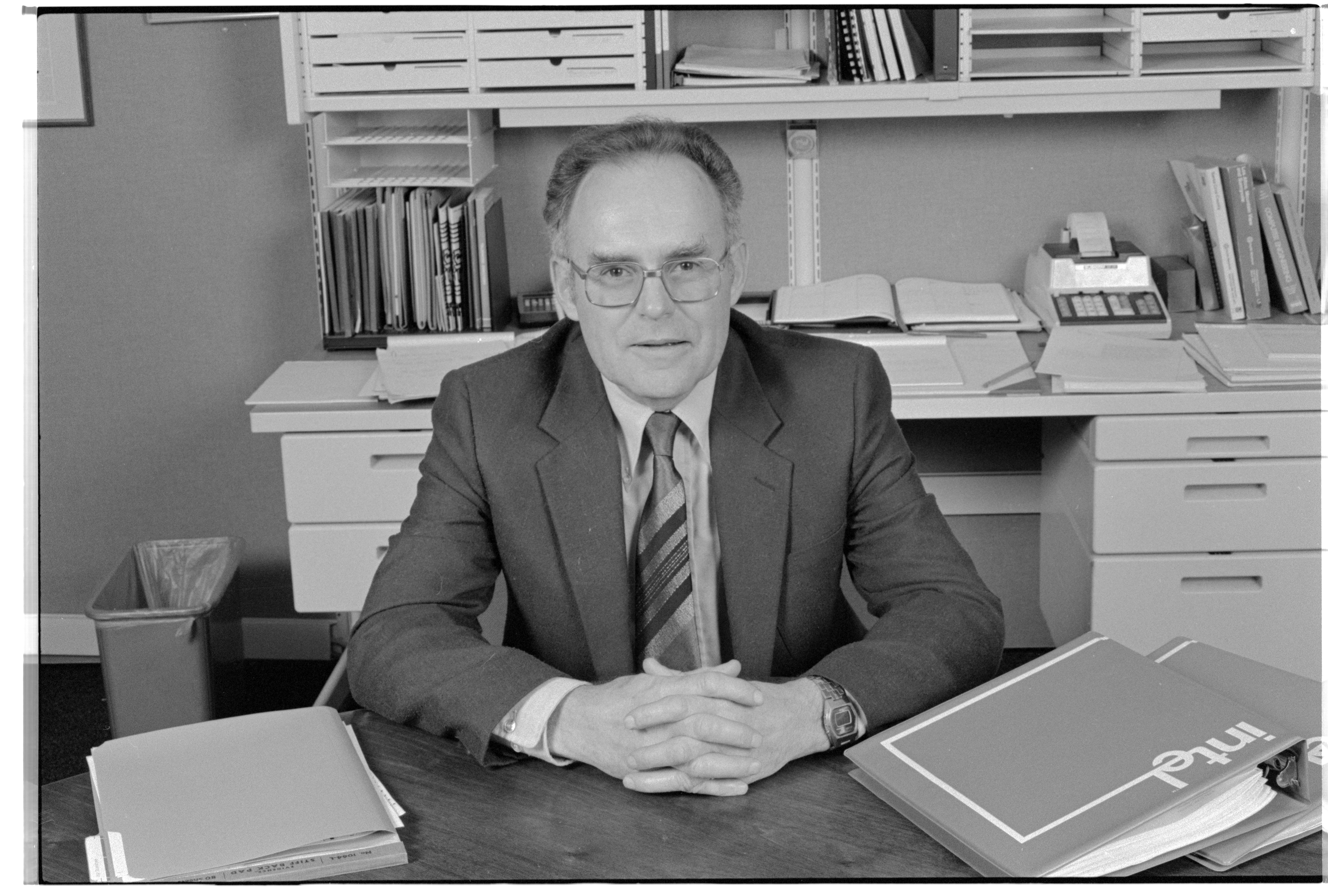 Gordon Moore, CEO of Intel, seated behind an office desk.