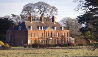 The brick exterior of Princess Kate and Prince William's Anmer Hall in front of a field