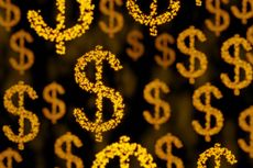 Dollar signs made of golden pellets randomly scattering in black background with bokeh effect. 