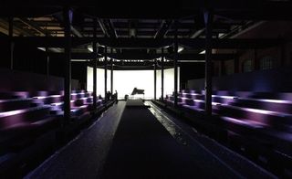 a dimly-lit space, with rows of purple benches lining the catwalk, which came topped by a grand piano