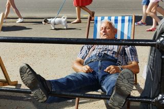Martin Parr photo on show at Photo London 2023 showing man asleep in deckchair with feet resting on promenade railings