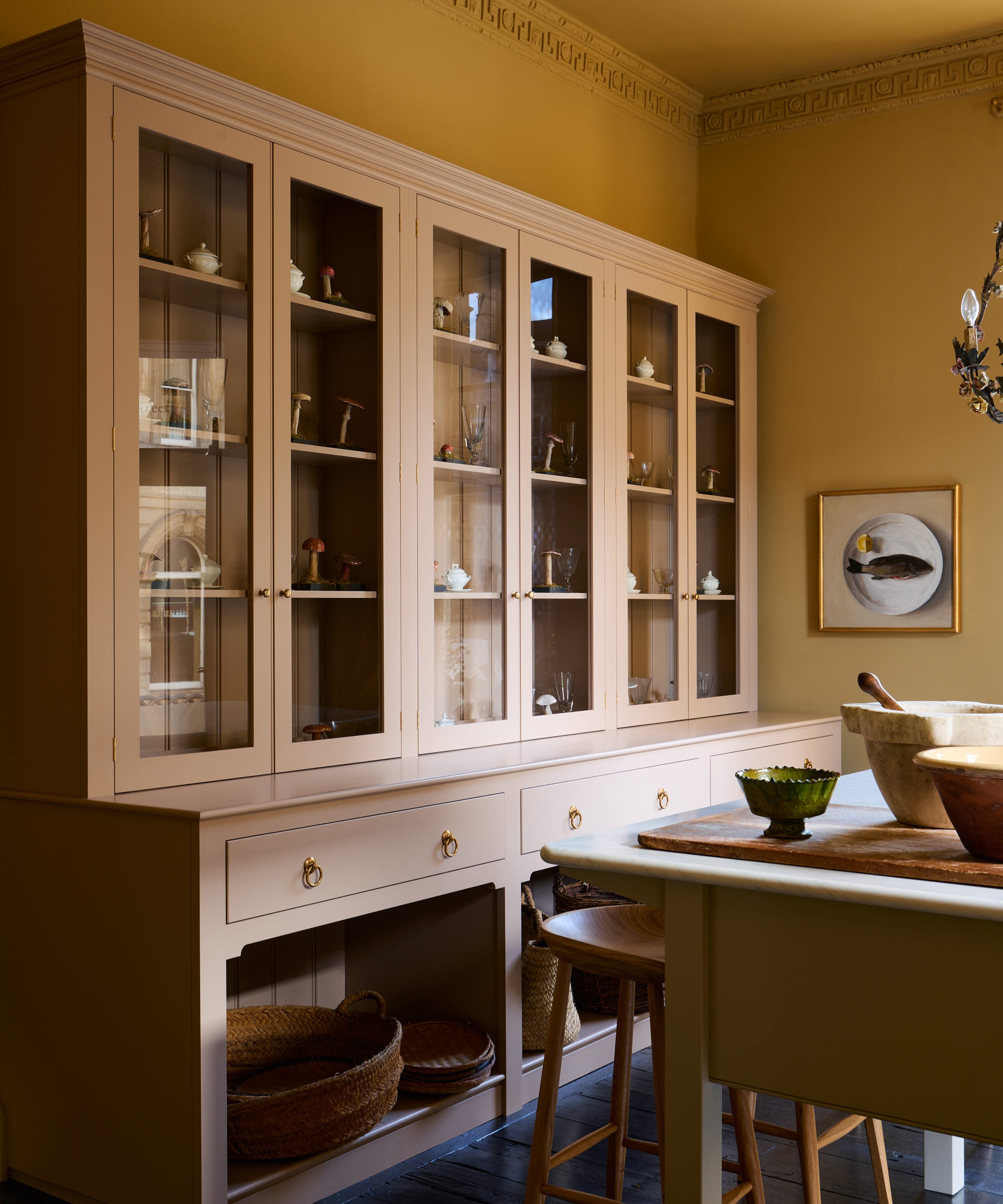 A yellow kitchen with a large pink hutch and a green freestanding island
