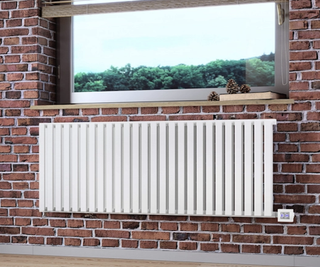 White modern electric radiator against a brick wall