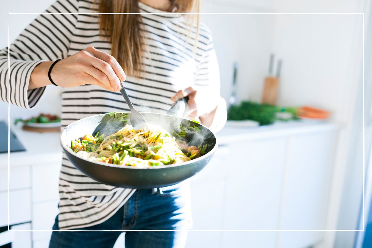 Woman in striped top, holding a pan with a cooked pasta dish