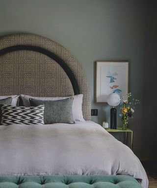 Green bedroom with white bed sheets and a curated nightstand