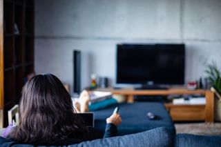 Woman sitting watching TV with her feet up