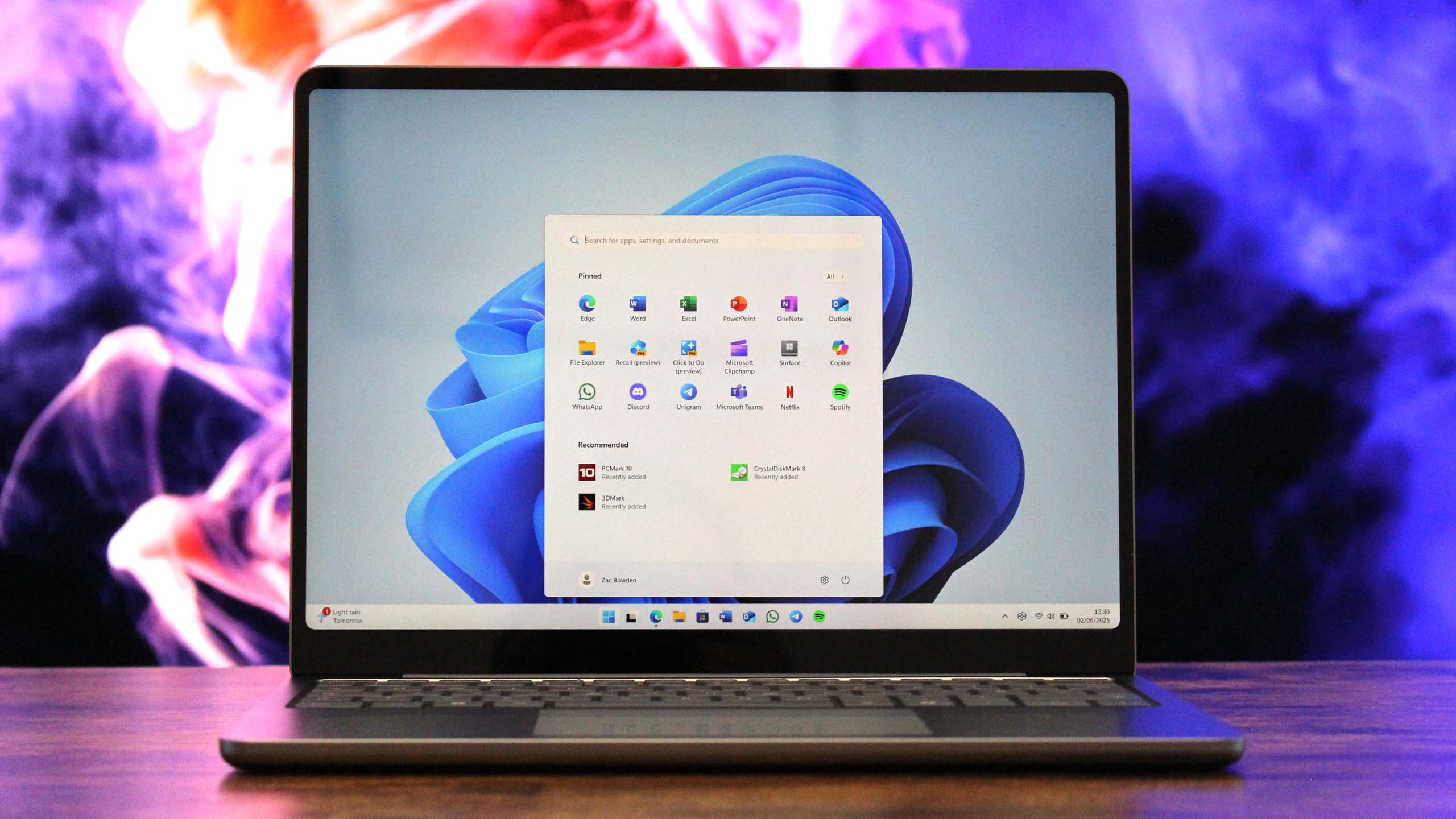 Surface Laptop 13-inch open on a wooden table in front of abstract visuals.