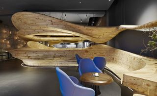 Raw restaurant withundulating wood-hewn sculptures and pale purple dining chairs