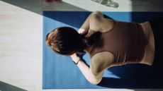 Woman demonstrating how to do a plank on a yoga mat with water bottle, wearing activewear, camera view from above
