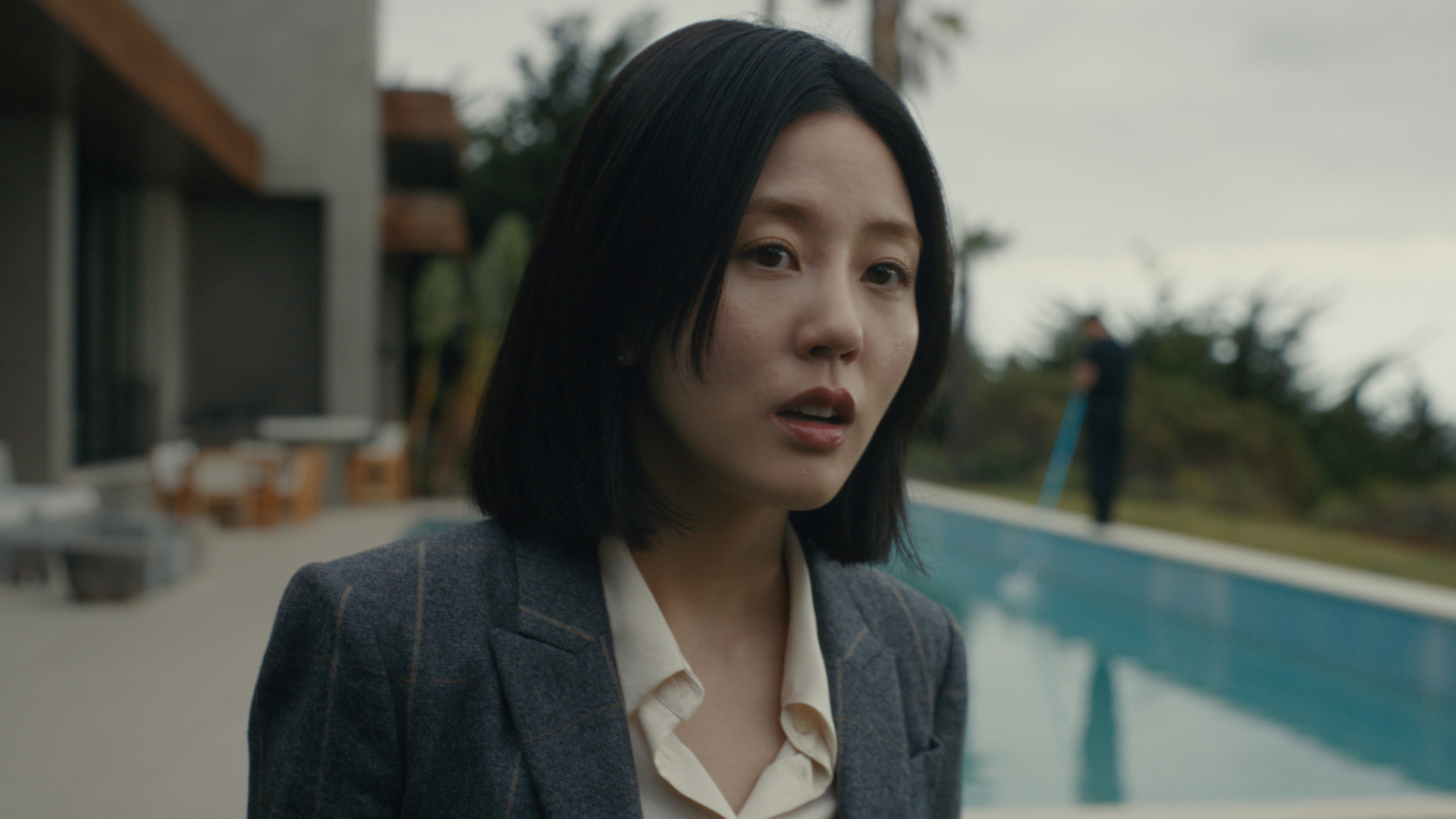 Seoyeon Jang as Eunice, standing outdoors in front of a pool, in episode 202 of Beef. 