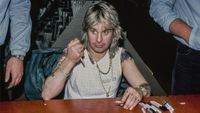 Heavy metal singer Ozzy Osbourne seated at a table during an autograph session, 1st March 1984, during the Ozzy/Motley Crue tour