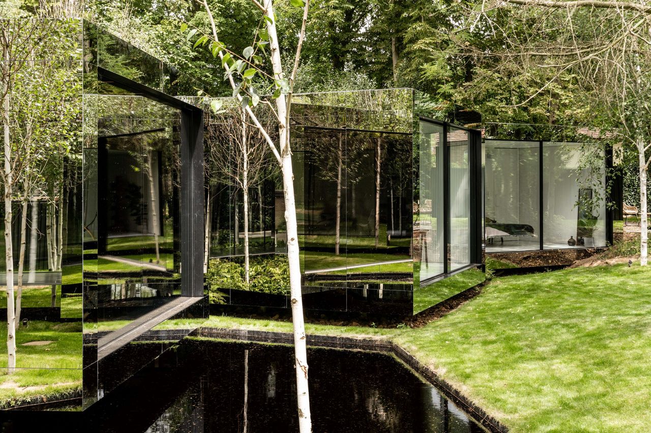 The mirrored walls can be seen through the garden and they reflect the surrounding woodland